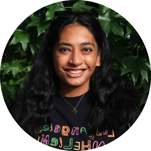 Woman with black t-shirt smiling in front of leaves.