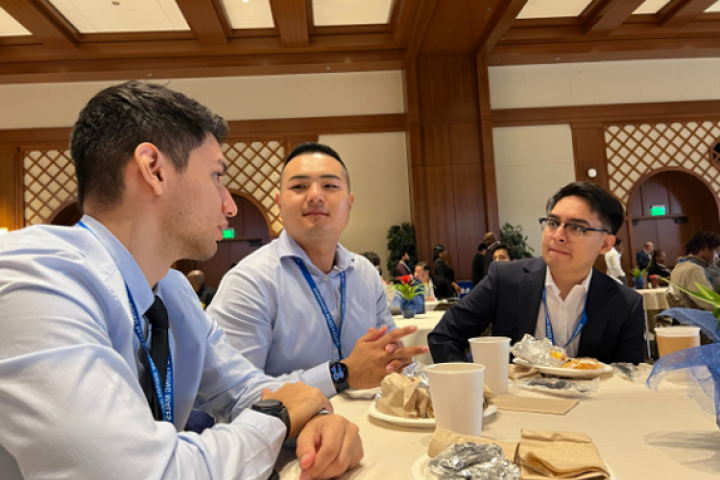 Three men in business attire talking at a table.